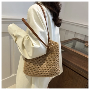 Detail of hollow-out woven tote bag with brown leather shoulder strap on a model