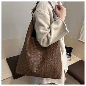 Detailed view of dark brown woven leather tote bag texture and large shoulder strap
