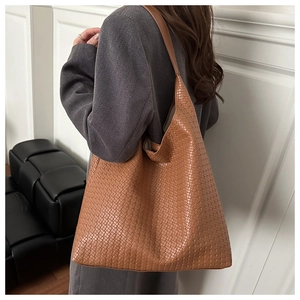 Close-up of brown woven texture tote bag with leather shoulder straps for women