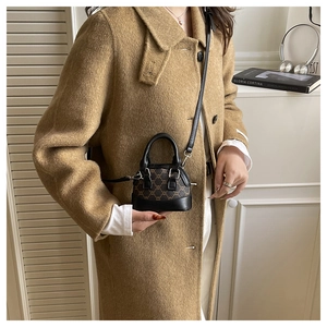 Close-up of mini shell bag with retro pattern and black leather accents on a model