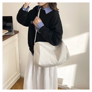 Photo lifestyle d'un sac fourre-tout crème avec bandoulière large sur un mannequin