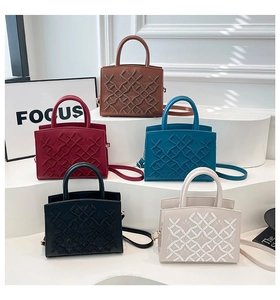Five assorted patent leather tote bags with diamond stitching on display stands