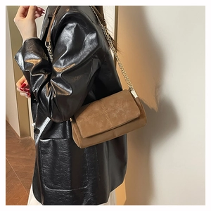 Brown suede crossbody bag with metal chain strap and decorative cross stitching