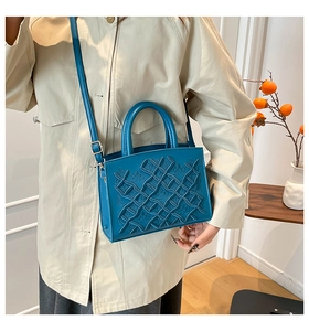 Close-up of the woven texture with crown embossing on the blue Lady bag worn with a coat