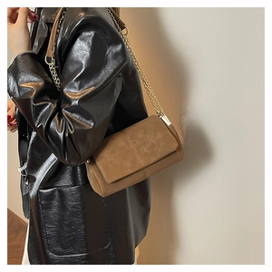 Brown suede crossbody bag with quilted stitching and gold chain strap on model