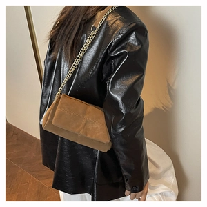Detail of vintage brown suede crossbody bag with gold chain and quilted stitching