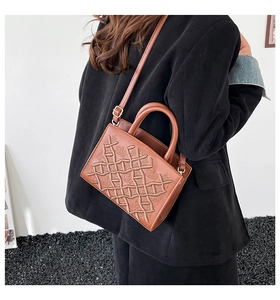 Detail of a brown crossbody bag with embossed floral pattern worn by a model