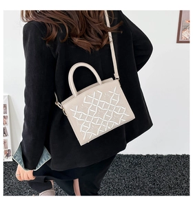 Detail of beige embroidered tote bag with floral grid pattern and gold hardware