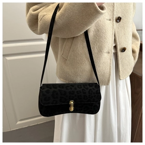 Detail view of black leopard print underarm bag with gold metal buckle on model