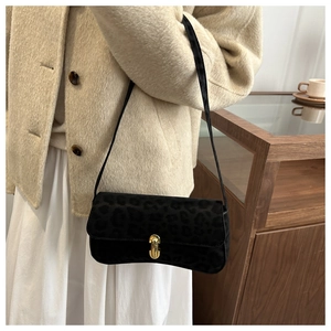 Detail of black leopard print faux suede underarm bag with golden twist lock closure