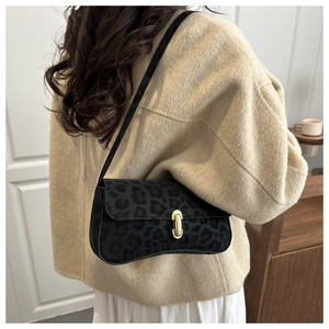 Detailed view of a vintage leopard print shoulder bag with a gold metal clasp on a beige coat