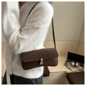 Detail of vintage brown suede shoulder bag featuring subtle leopard print and gold metal lock