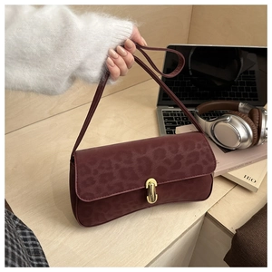 Detail of burgundy leopard print suede underarm bag with elegant gold buckle hardware