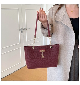 Close-up of wine red leopard print tote bag with golden deer pendant and chain detail