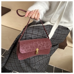 Close-up of wine red faux suede baguette bag with leopard texture and gold clasp