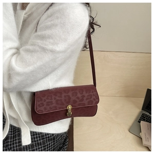 Detailed view of leopard print baguette bag in burgundy with gold metal lock buckle