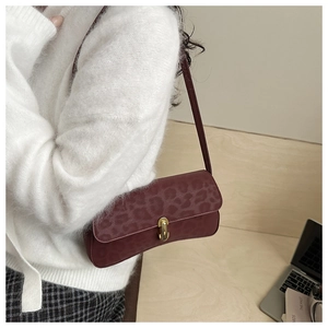 Detail of burgundy leopard print underarm bag with gold oval twist lock and strap