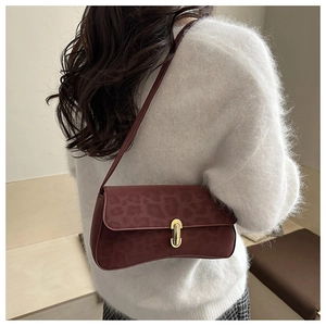 Close-up of burgundy suede shoulder bag featuring leopard texture and gold metal buckle