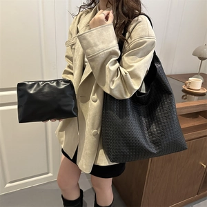 Fashionable black woven PU leather tote bag with matching pouch on model in a cozy room