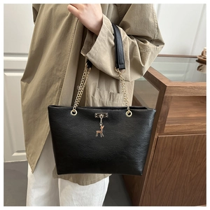 Detail of black PU leather tote with gold deer charm and chain shoulder strap