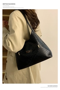 Detail shot of black leather tote bag with textured finish and elegant gold buckle