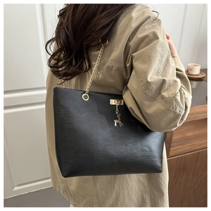 Details einer schwarzen Ledertasche mit Goldkette und Hirsch-Anhänger am Modell