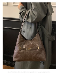 Detail of dark brown woven leather shoulder bag featuring golden metal interlocking buckle