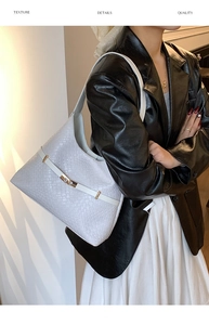 Detail of white woven hobo bag with gold buckle on a model in a black leather jacket
