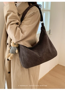 Deep brown suede shoulder bag detail with minimalist stitching and teddy bear charm