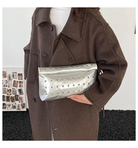 Gros plan d'une pochette enveloppe argentée à rivets sur fond de manteau en laine