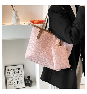 Pink woven bucket bag with matching clutch, shown worn over shoulder with sleek black blazer