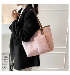 Dettaglio della borsa tote rosa con stampa coccodrillo e manici marroni su un modello