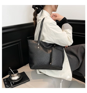 Detailed view of black woven tote bag and matching pouch on a fashion model