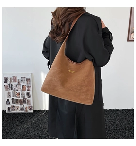Détail du sac cabas en daim marron avec lettrage doré et texture de haute qualité