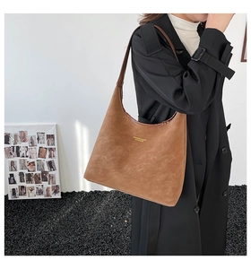 Detail of a large brown suede tote bag featuring gold lettering and matte texture