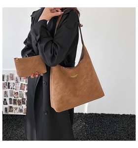 Detail of brown suede hobo tote with matching pouch and gold foil fashion logo lettering