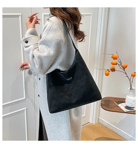 Detail of black suede hobo bag with gold logo on gray coat for commute style