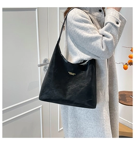 Detail of black suede hobo bag featuring a gold fashion logo on premium texture