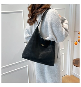 Detail view of large black tote bag with gold brand lettering and elegant matte finish