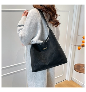 Detailed macro view of the minimalist large black leather tote bag with gold lettering