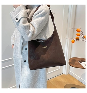 Vue détaillée du grand sac cabas en cuir marron foncé avec lettrage doré sur un manteau