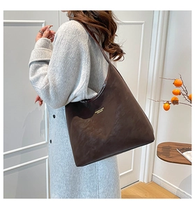 Détail d'un grand sac fourre-tout marron foncé porté par un mannequin en manteau gris