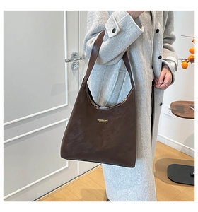 Detail of vintage dark brown faux leather hobo bag with gold logo and shoulder strap