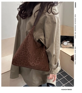 Detail of a large leopard print hobo bag worn by a model in a modern office setting