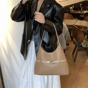 Brown snakeskin bucket bag with gold buckle shown in a cozy cafe setting