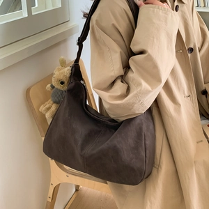 Borsa hobo vintage minimalista marrone scuro in pelle opaca indossata con trench beige