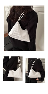 Detail of white textured corduroy shoulder bag showing woven grid pattern and slim straps