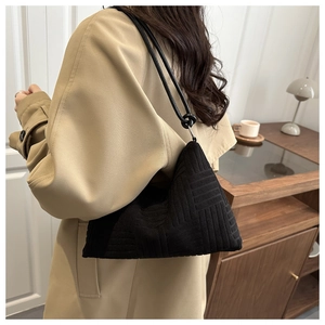 Detail of black geometric textured fabric handbag with knotted strap for women