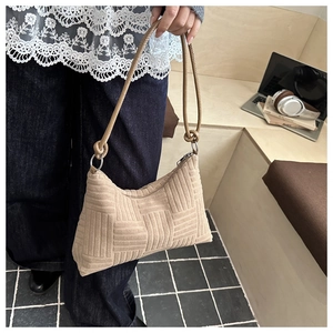 Détail de la texture tissée du sac à bandoulière beige avec nœud décoratif sur l'anse