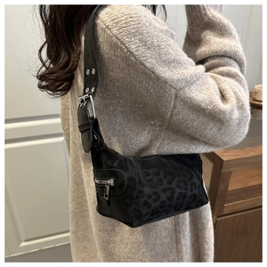 Detail of black leopard print shoulder bag with decorative side zipper and silver buckle